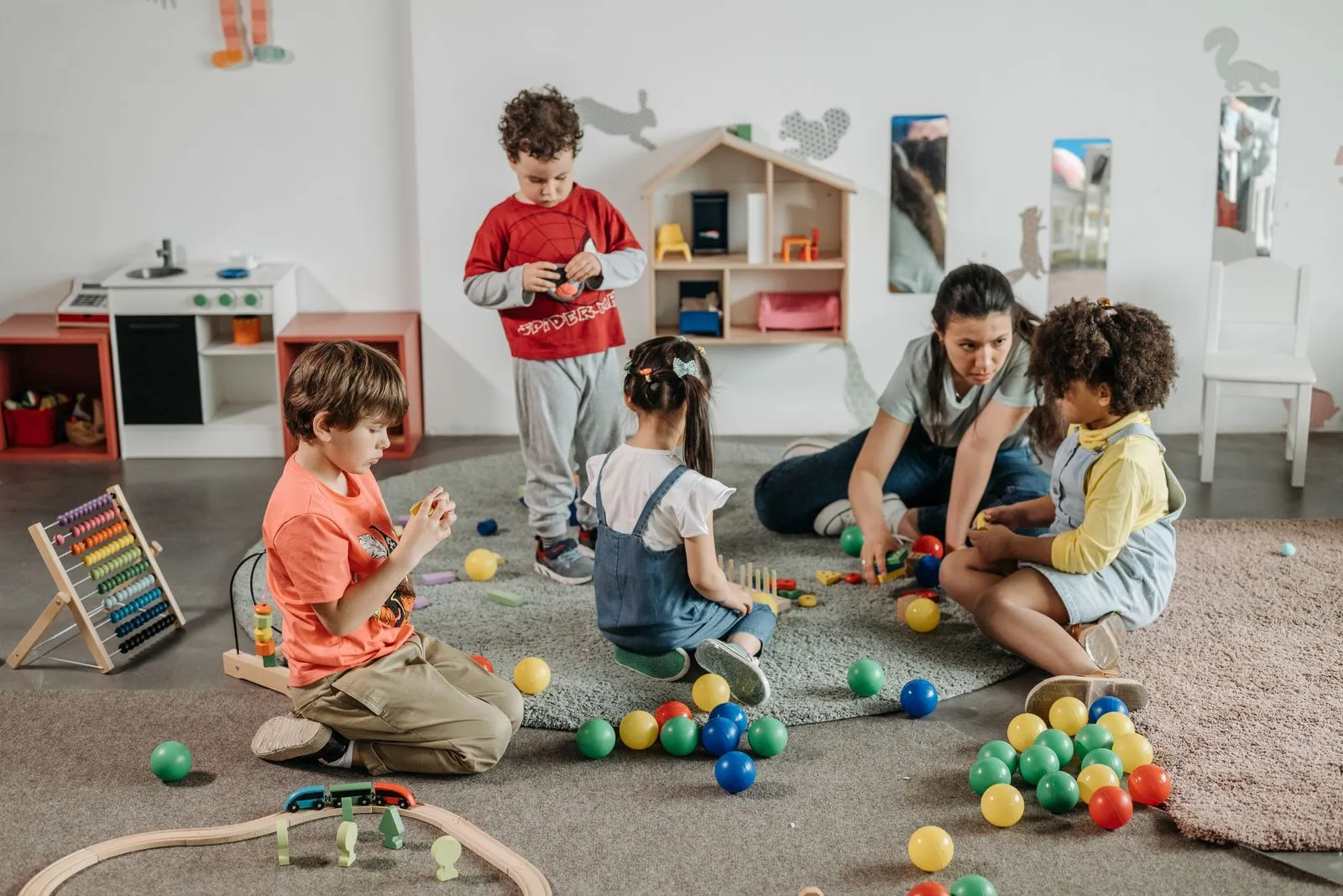 Profissional brincando com um grupo de crianças em sala com brinquedos